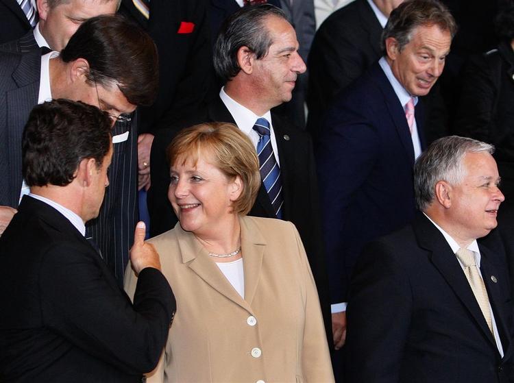 Den franske præsident Nicolas Sarkozy gestikulerer til den tyske kansler Angela Merkel under optagelsen af fotos til EU-familiealbummet. Ved siden af Merkel står den polske præsident Kaczynski. 