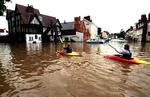 I Nordengland padler to personer i kano mellem de oversvømmede huse. 