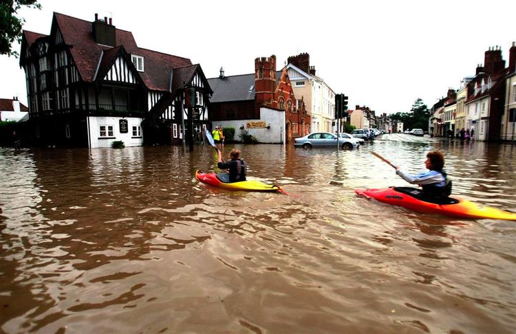 I Nordengland padler to personer i kano mellem de oversvømmede huse. 