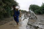 Tusinder af pakistanere er isoleret af vandmasser efter heftig storm i landet. Her krydser folk et lille vandløb ved Larkha. 