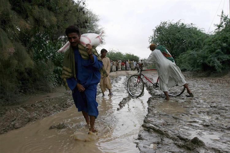 Tusinder af pakistanere er isoleret af vandmasser efter heftig storm i landet. Her krydser folk et lille vandløb ved Larkha. 
