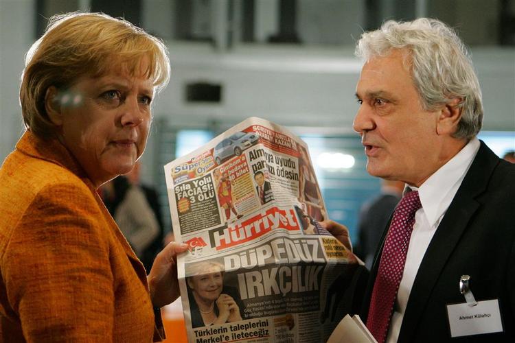 Den tyske kansler Angela Merkel og journalist Ahmet Kuelahci holder den tyrkiske avis 'Hurriyet' forud for dagens integrationskonference i Berlin. Overskriften på avisen er ifølge AP »Duepeduez Irkcilik« - som betyder noget i retning af 'Ganske enkelt racisme'. 