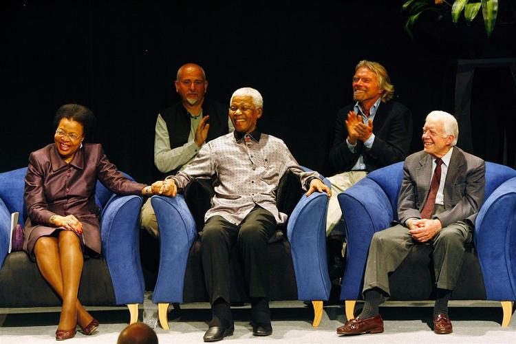 Nogle af de prominente medlemmer ses her, mens de lytter til ærkebiskop Desmond Tutu: Fra venstre Graça Machel, hendes mand Nelson Mandela og USA's tidligere præsident Jimmy Carter. Bag dem ses pengemændene Peter Gabriel og Richard Branson. 