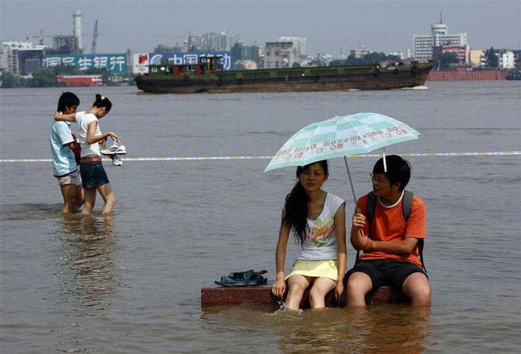 Et par sidder på en bænk ved  Yangtze-floden i Kina, der er ramt af voldsomme oversvømmelser. 