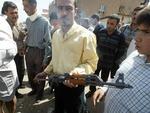 En mand vil sælge en AK-47 Kalashnikov riffel på et marked i Bagdad. Billedet er fra april 2003, hvor stjålne varer fra tiden efter Saddam Hussein blev solgt til spotpris. 