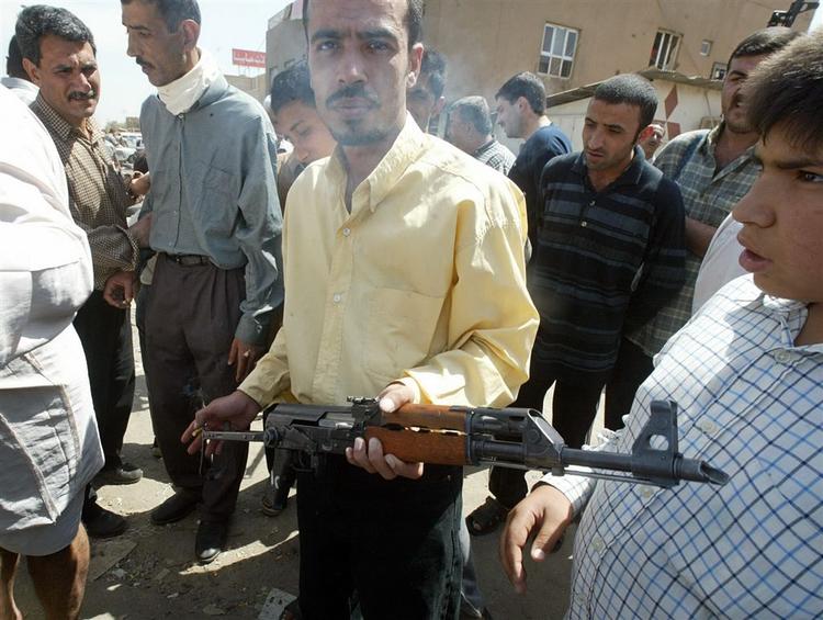En mand vil sælge en AK-47 Kalashnikov riffel på et marked i Bagdad. Billedet er fra april 2003, hvor stjålne varer fra tiden efter Saddam Hussein blev solgt til spotpris. 