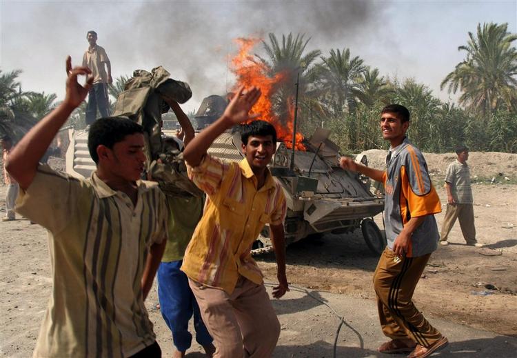 Irakere jubler ved siden af det brændende danske køretøj i Basra. 
