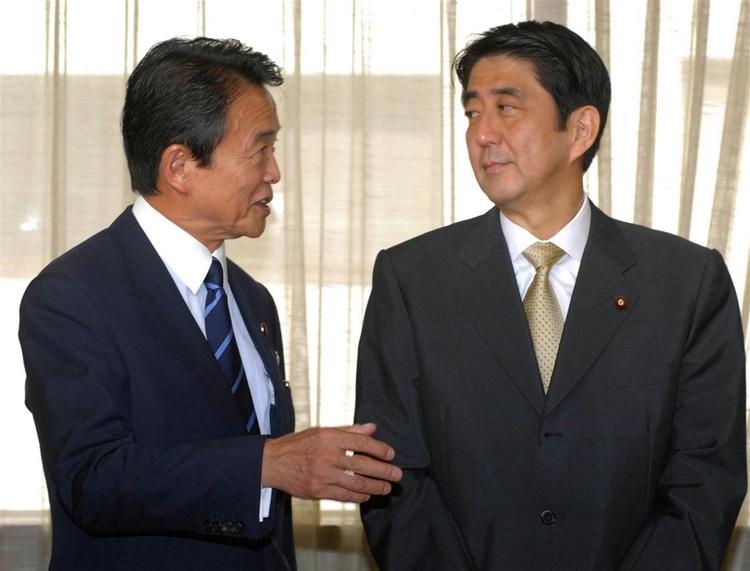 Premierminister Shinzo Abe til højre lytter til udenrigsminister Taro Aso efter mødet i Det Liberale Demokratiske Parti. 