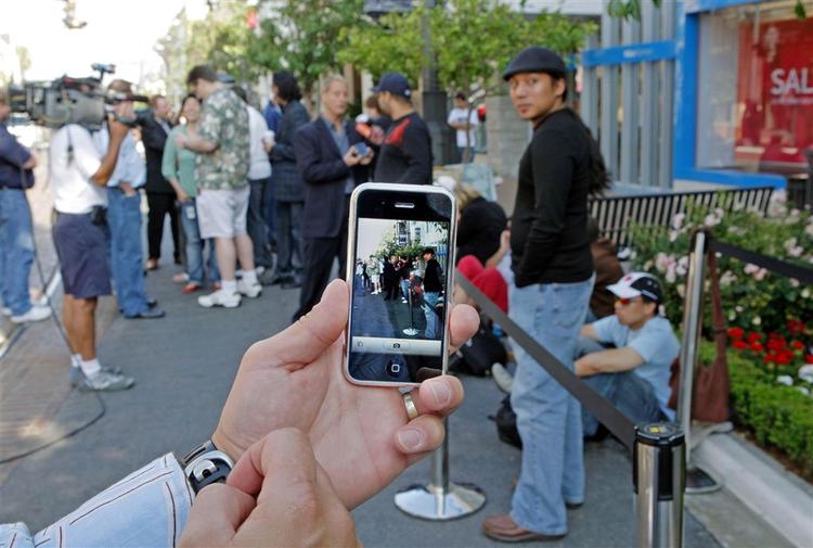 Apples seneste produkt er iPhone - som her fotograferer kunder, der står i kø for at købe dette vidunderapparat. Apple er måske nu på vej ind i bilbranchen. 