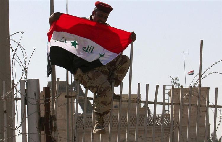 En irakisk soldat hejser flaget på paladset, der tidligere var base for de britiske styrker i Basra. 