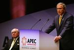 Bush på podiet i Sydney Opera House lige inden det hele begynder at gå skævt. Til venstre mødets vært John Howard. 