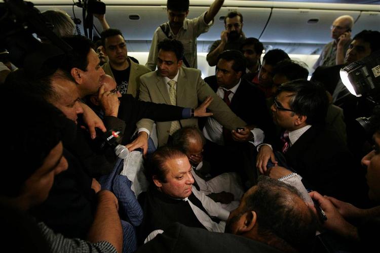 Sharif omgivet af tilhængere, kontrollanter og journalister i den overfyldte flykabine kort efter touch down i Pakistan. 
