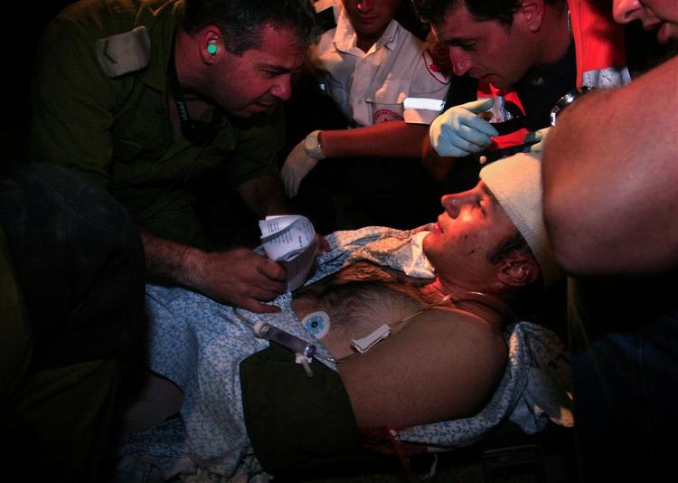 En såret israelsk soldat føres væk, efter en palæstinensisk raket har ramt et militærtelt fyldt med soldater i Israel. 
