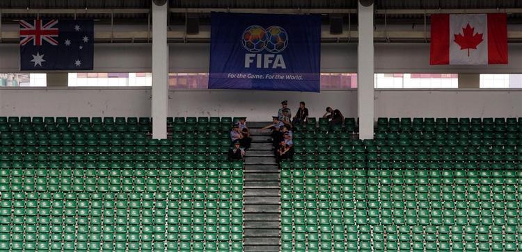 Kinesiske betjente er alene på stadion i Shengdu efter, at gruppe C-kampen mellem Australien og Canada blev aflyst på grund af vejret. 