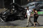 Et par går forbi resterne af den bil, som den dræbte libanesiske politiker Antoine Ghanem kørte i onsdag. 