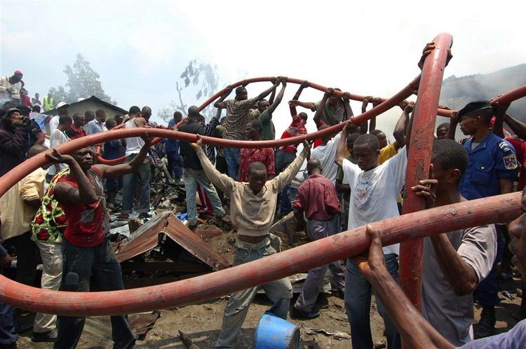 Frivillige hjælper med at føre en brandslange frem til de flammer, der opstod, da et transportfly tidligt torsdag styrtede ned i DR Congos hovedstad, Kinshasa. 