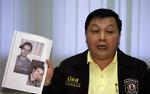 Politiinspektør Wimol Powintara, holder billedet af den eftersøgte canadier op ved udstedelsen af arrestordren i Bangkok i går. 