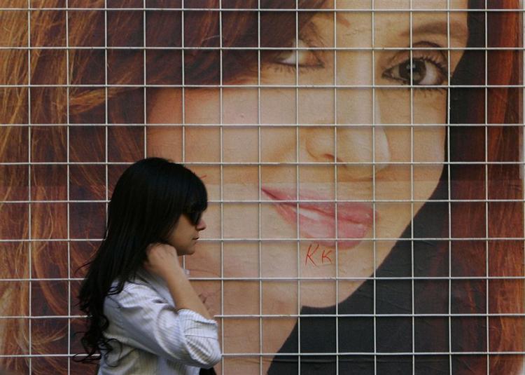 En kvinde går forbi en valgplakat med den 54-årige præsidentfrue  Cristina Fernández, der spås gode chancer for at vinde valget. 