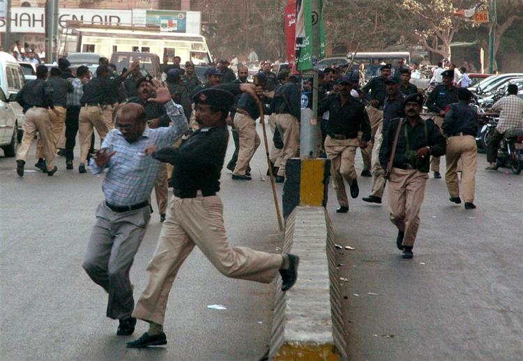 Pakistansk politi overfalder en lokal journalist under demonstrationer mod præsident Pervez Musharraf. 