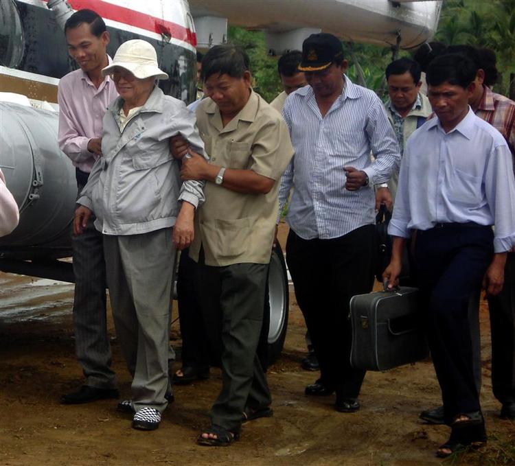 Khieu Samphan (med hvid hat) føres til den helikopter, der bringer ham til et hospital i hovedstaden. 
