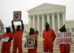 Menneskerettighedsaktivister i orange fængselsdragter demonstrerer uden for højesteret i Washington under retssagen om Guantánamofangernes rettigheder. 