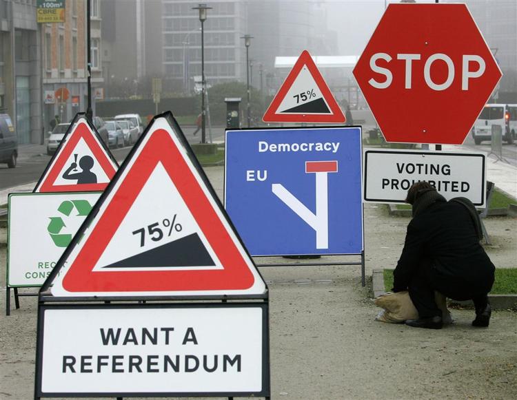 Demonstranter satte vejskilte med politiske budskaber op ved EU's hovedkvarter i Bruxelles, hvor statslederne i dag underskrev reformtraktaten. 
