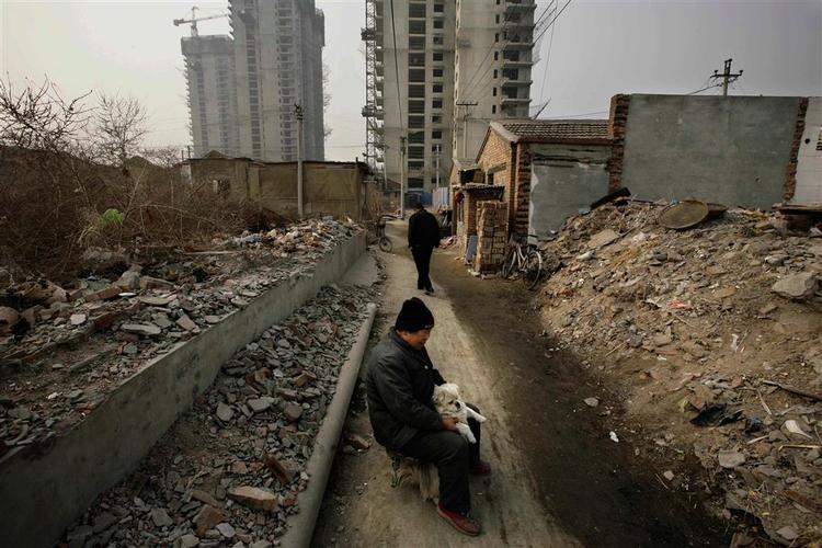 En kvinde holder sin hund, efter hendes hus er blevet jævnet med jorden i Bejing, Kina. 