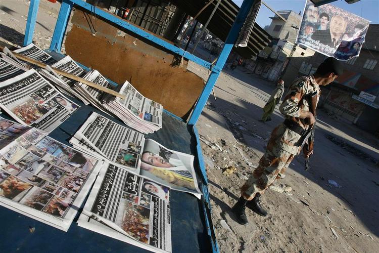 En pakistansk soldat holder vagt i Larkana, foran aviser prydet af historien om attentatet på Bhutto. 