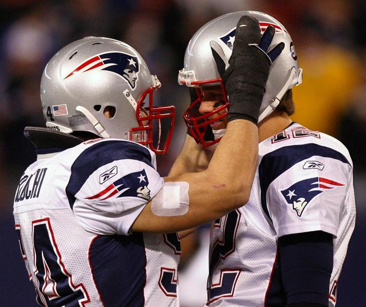 New England Patriots linebacker Tedy Bruschi (tv.) lykønsker sin quarterback Tom Brady, som med to kastede touchdowns satte ny rekord med i alt 50 af slagsen i grundspillet. 