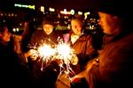 På tærsklen til år 2008 tænder feststemte mennesker stjernekastere på Dronning Louises Bro 