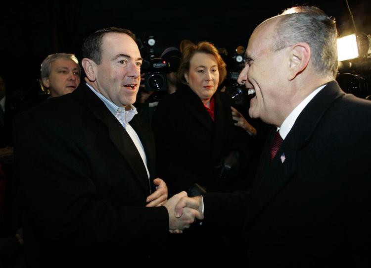 Mike Huckabee (tv.) hilser på Rudy Giuliani, mens vælgerne afgiver deres stemme i Manchester, New Hampshire. 