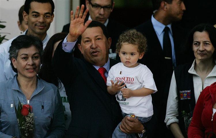 Hugo Chavez vinker til presse og publikum, mens han holder Consuelo Gonzalez' barnebarn. Consuelo selv står til venstre, men det andet frigivne gidsel, Clara Rojas, står til højre for præsidenten. 
