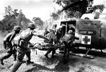 Amerikanske tropper fra 173. luftbårne brigadebærer en såret kammerat om bord på en ambulance- helikopter nord for Saigon den 29. juni 1965. 