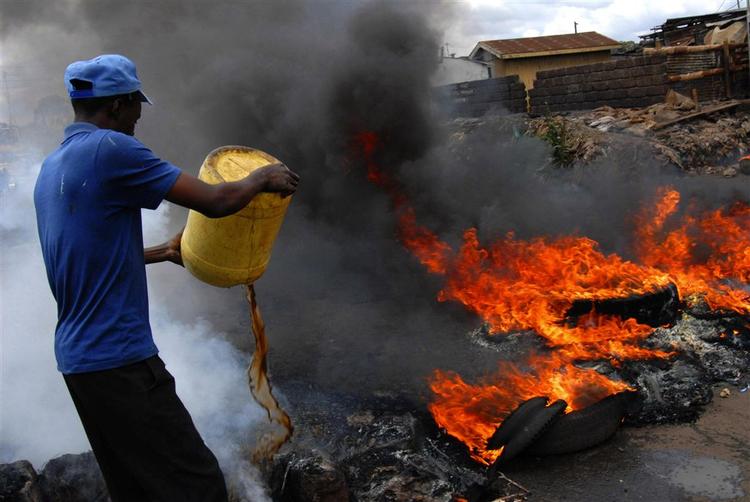 En beboer i slumområdet Kibera i Nairobi forsøger at slukke en påsat brand. 