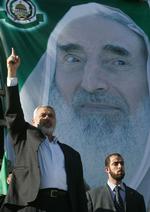 Hamas-leder Ismail Haniey foran plakat med sidste Hamas-leder Ahmed Yassin. Hamas ankalger Fatah for at ville slå ham ihjel. 