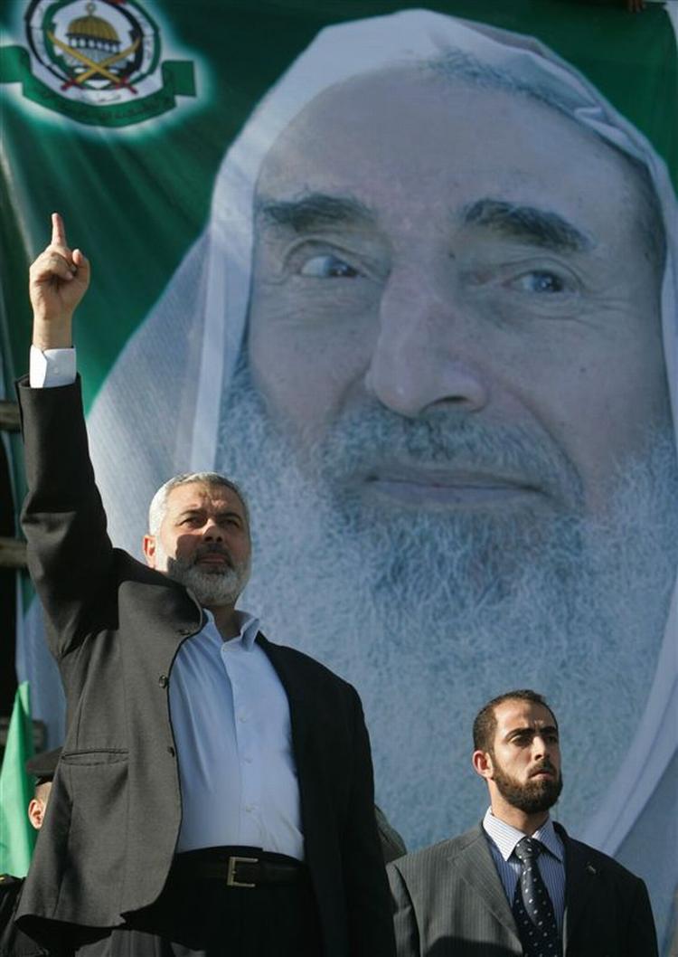 Hamas-leder Ismail Haniey foran plakat med sidste Hamas-leder Ahmed Yassin. Hamas ankalger Fatah for at ville slå ham ihjel. 