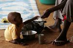 Et somalisk barn tager imod mad fra sin far i flygtningelejren Dadaab i det nord- lige Kenya. Somalia er et af de lande, hvor det mest markant er lykkedes at nedbringe børnedødeligheden ved at sikre en bedre koordinering af forskellige bistandsprogrammer.  Foto: Karel Prinsloo/AP 