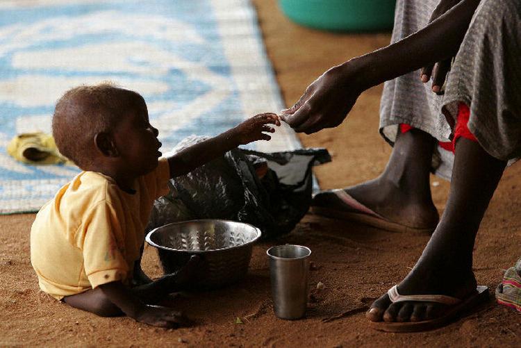 Et somalisk barn tager imod mad fra sin far i flygtningelejren Dadaab i det nord- lige Kenya. Somalia er et af de lande, hvor det mest markant er lykkedes at nedbringe børnedødeligheden ved at sikre en bedre koordinering af forskellige bistandsprogrammer.  Foto: Karel Prinsloo/AP 