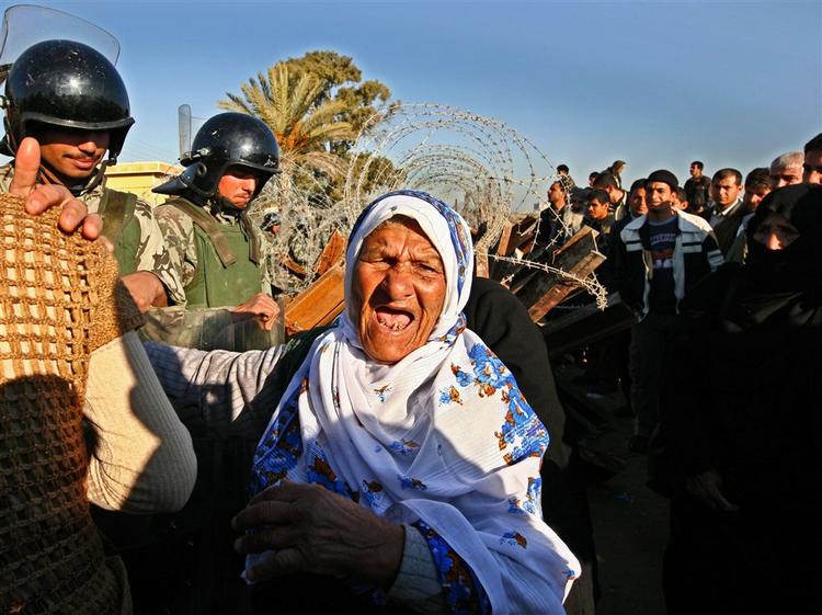Egyptiske soldater standser en palæstinensisk kvinde, der vil gennem hullet i grænseovergangen mellem Egypten og Gaza. 