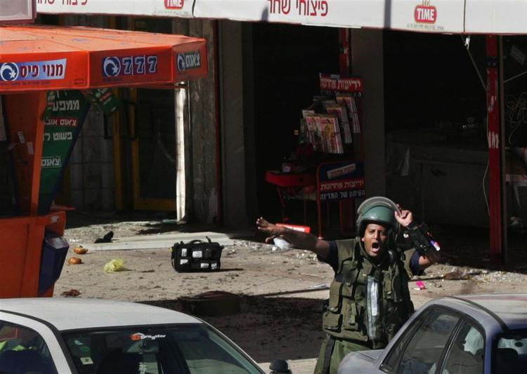 En israelsk politimand råber ordrer ved det sted, hvor et selvmordsangreb i går dræbte en israelsk kvinde. 