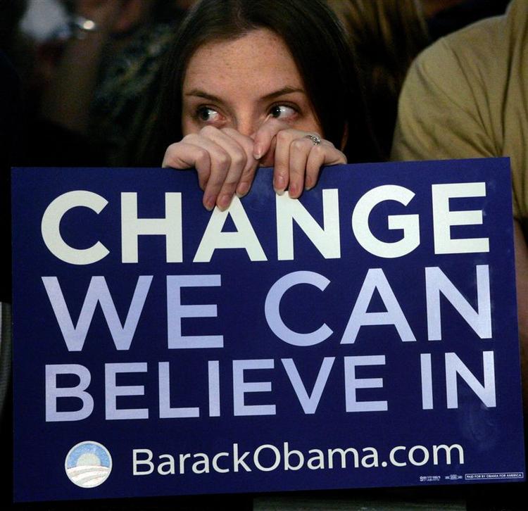 En Obama-tilhænger titter frem bag et skilt med sloganet 'Change We Can Believe In'. Og demokraterne rider på en bølge af entusiasme på grund af netop kravet om forandring, mener redaktør på Washington-baseret avis. 