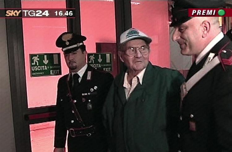 Michael Seifert blev fulgt fra flyet af militærpolitibetjente. Vidner sagde under retssagen mod ham i 2000, at han lo, mens han torturerede fangerne af nazisterens fangelejr i Bolzano i 1944-1945. Foto fra tv. 