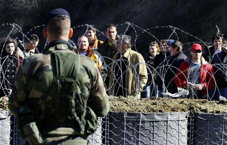 En fransk NATO-soldat holder vagt ved en gruppe serbiske demonstranter, efter at NATO-styrkerne har generobret en grænsepost, som blev brændt ned af vrede serbere i går. 