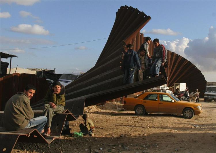 Palæstinensere sidder ved den del af grænsehegnet, der blev ødelagt i januar mellem Gaza og Egypten. 