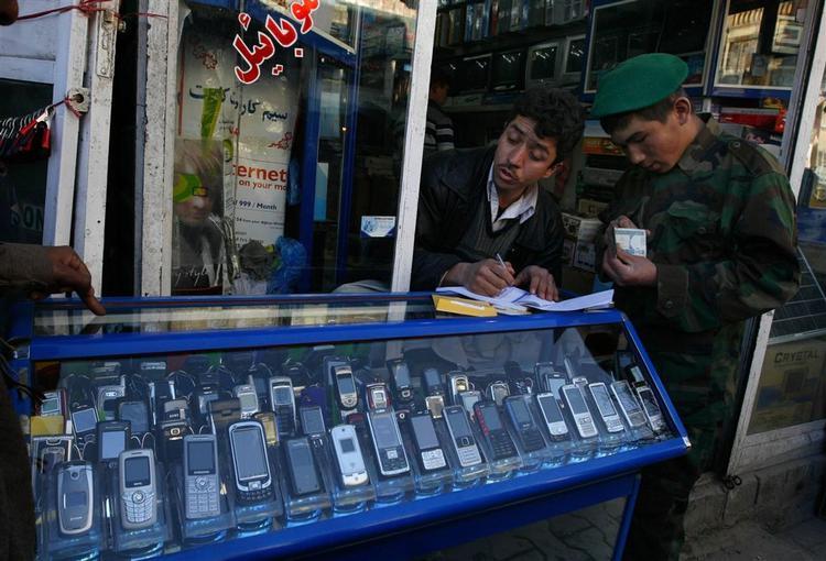 En afghansk mobiltelefonsælger skriver en kvittering til en kunde. 