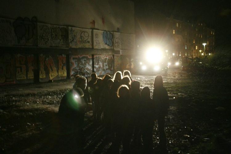 Nogle unge autonome opholder sig på grunden på Jagtvej 69, der husede Ungdomshuset. Imens holder politiet øje med dem i projektørlyset. 