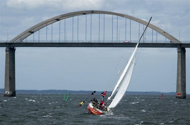 En sejlbåd kæmper mod vinden ud for Rudkøbing med Langelandsbroen i baggrunden. Arkivfoto. 