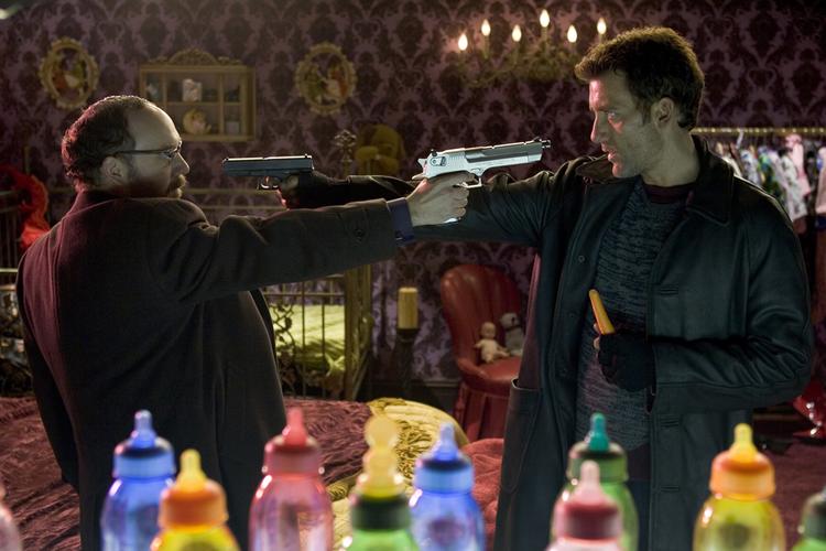 Clive Owen (th.) som revolvermanden Mr. Smith, der får ansvaret for en nyfødt baby, som den onde forbryderkonge Mr. Hertz, spillet af Paul Giamatti, vil  til livs (Foto fra filmen). 