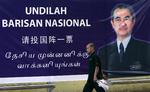 En malaysier passer en stor valgplakat med regeringschefen Abdullah Ahmad Badawi, som blev straffet af vælgerne. 