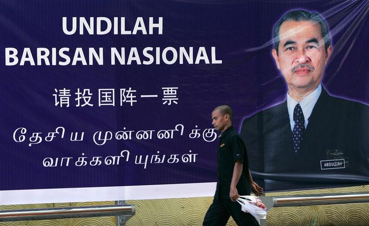 En malaysier passer en stor valgplakat med regeringschefen Abdullah Ahmad Badawi, som blev straffet af vælgerne. 